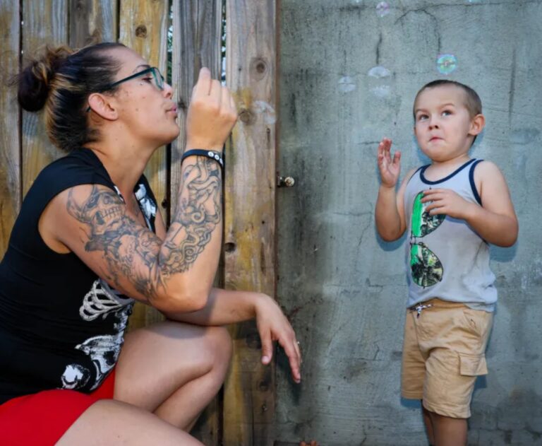 A mother blows bubbles while her little boy looks on